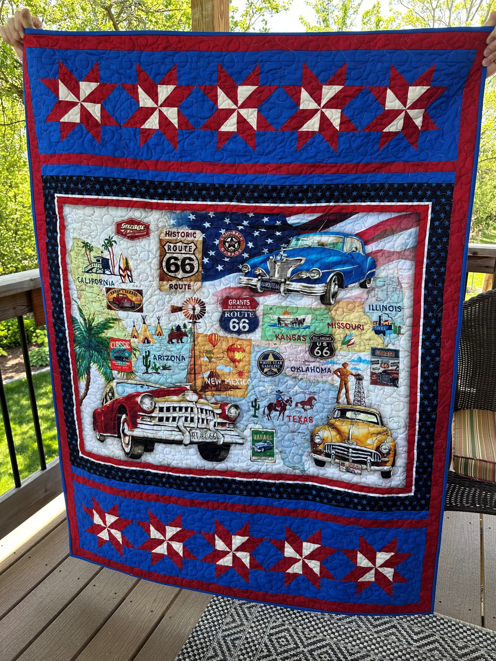 Red, white, and blue Route 66 themed quilt with pictures of classic cars, road side attractions, and Americana.