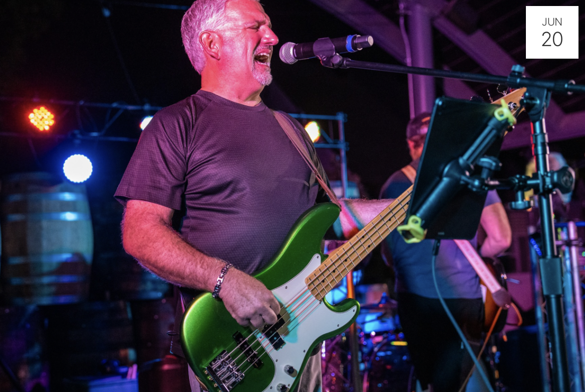 Image of man playing a green electric guitar and singing live music
